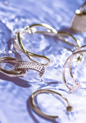 金手镯耳环环Jewelery紫色的水背景奢侈品魅力假期美设计珠宝品牌广告