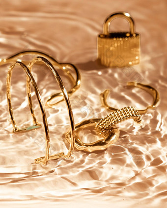 金手镯耳环环Jewelery黄金水背景奢侈品魅力假期美设计珠宝品牌广告