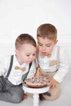 男孩庆祝生日孩子们生日聚会，派对孩子们吹蜡烛生日蛋糕庆祝活动白色极简主义室内