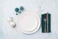 圣诞节表格设置白色餐具银器绿色装饰蓝色的背景前视图