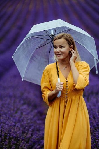 中年女人薰衣草场走伞多雨的一天享受芳香疗法芳香疗法概念薰衣草石油照片会话薰衣草