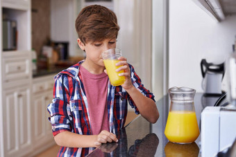 帮助汁年轻的男孩喝玻璃橙色汁