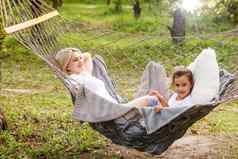 美丽的年轻的妈妈。女儿铺设放松吊床阳光明媚的夏天一天假期首页花园家庭放松在户外健康的健康生活方式