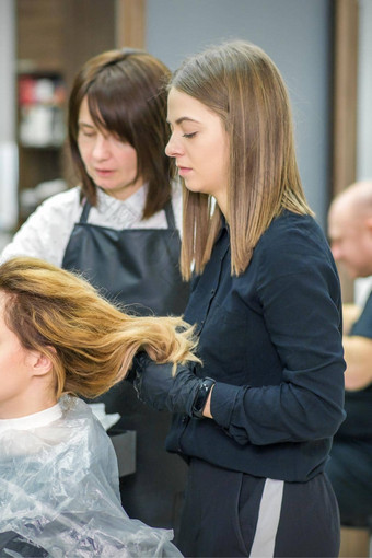 女发型师准备长头发年轻的女人使卷发发型美沙龙