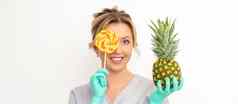美丽的微笑美容师持有新鲜的菠萝封面眼睛棒棒糖白色背景护肤品清洗生态有机