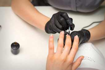绘画指甲女人手指甲修饰师黑色的手套应用透明的指甲波兰的女指甲美沙龙