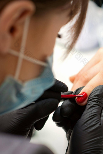 绘画指甲女人手指甲修饰师黑色的手套应用红色的指甲波兰的女指甲美沙龙