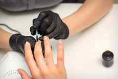 绘画指甲女人手指甲修饰师黑色的手套应用透明的指甲波兰的女指甲美沙龙
