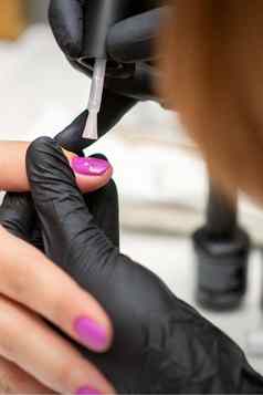 绘画指甲女人手指甲修饰师黑色的手套应用粉红色的指甲波兰的女指甲美沙龙