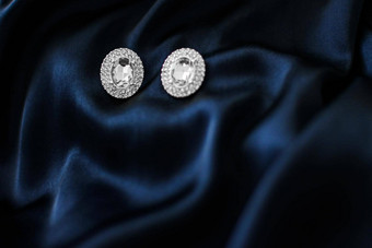 奢侈品钻石耳环黑暗蓝色的丝绸背景假期魅力Jewelery现在