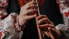 手女人玩木管乐器木长笛乌克兰索皮尔卡黑暗背景人音乐概念音乐的仪器音乐家传统的绣花衬衫维希万卡