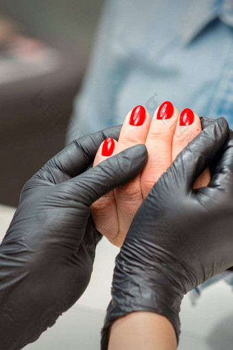检查修剪整齐的指甲手修指甲主黑色的手套检查女红色的指甲修指甲沙龙