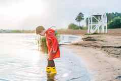 男孩红色的雨衣黄色的橡胶靴子玩水海滩学校孩子防水外套跳水海孩子有趣的波海岸