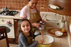 美丽的孩子欧洲女孩酋长围裙站厨房工作台面妈妈揉捏面团