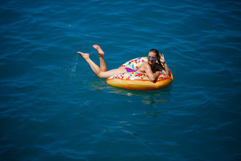 美丽的快乐年轻的女人泳衣充气环放松蓝色的海阳光明媚的一天海边假期旅游