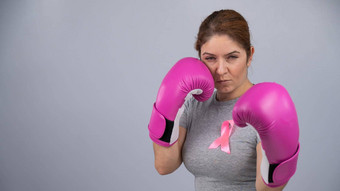 高加索人女人粉红色的拳击手套粉红色的丝带胸部灰色的背景战斗<strong>乳房癌症</strong>