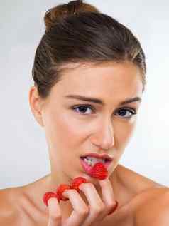 渴望的新鲜的水果肖像华丽的年轻的女人吃树莓手指工作室