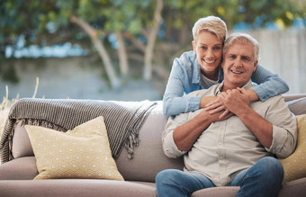 成熟的夫妇爱债券拥抱房子天井首页花园沙发放松家具椅子后院肖像微笑快乐退休高级男人。女人信任安全安全