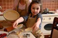 妈妈女儿围裙烹饪显示滚面团模具使自制的小果馅饼tarte