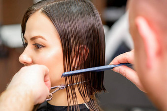 理发师削减湿头发年轻的高加索人女人梳理梳子头发沙龙