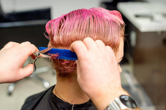 理发师削减染色湿粉红色的短头发年轻的高加索人女人梳理梳子头发沙龙