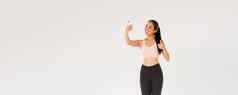 完整的长度微笑女生活方式博主亚洲健身女孩运动服装采取自拍健身房显示竖起大拇指演示锻炼exercies追随者在线生活流培训