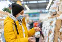 圣诞节装饰购物高加索人女人选择一年装饰购物购物中心媒介年龄女穿着医疗面具黄色的冬天派克大衣购买圣诞节点缀