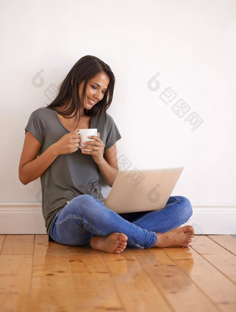 无线connectivit年轻的女人坐着地板上首页喝咖啡移动PC