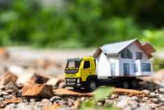 特写镜头小玩具卡车树树桩携带微型房子模型前模糊森林背景前面视图农村搬迁服务概念