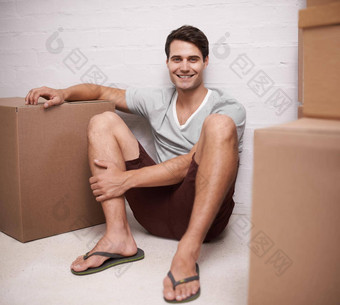 兴奋移动的地方快乐年轻的男人。坐着地板上首页包装纸板盒子