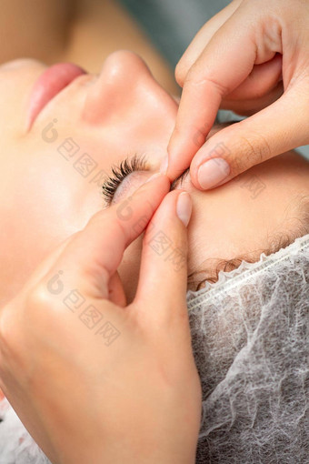 手册雕刻脸按摩水疗中心手指美容师使面部按摩眉年轻的女人美容诊所关闭