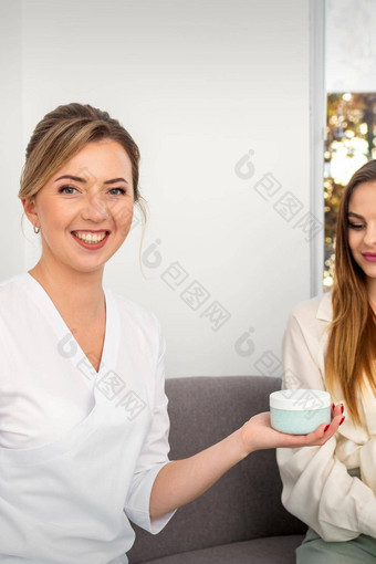 美容师提供产品年轻的女人显示拇指持有白色塑料Jar奶油模型复制空间