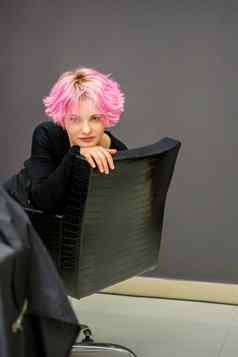 肖像美丽的年轻的高加索人女人短粉红色的发型坐着椅子理发师沙龙