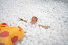 快乐女孩玩白色塑料球池娱乐公园操场上孩子们