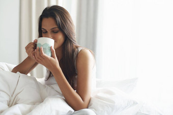 <strong>品味</strong>早....咖啡床上美丽的年轻的女人享受杯咖啡床上