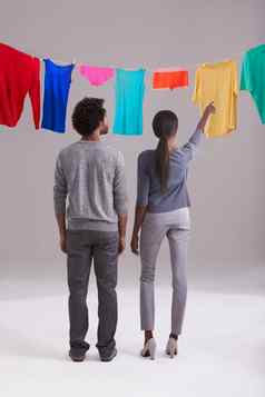 挂洗工作室拍摄年轻的夫妇站前面洗行完整的色彩斑斓的洗衣