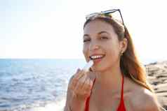 年轻的女人微笑相机应用太阳保护嘴唇海滩
