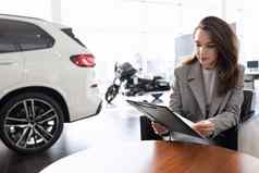 年轻的女人读取合同购买车车经销商信贷