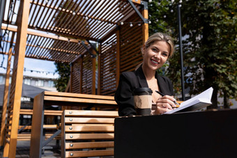 成功的女商人工作在户外喝咖啡使笔记日记