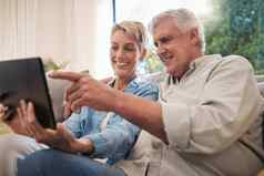 高级夫妇平板电脑社会媒体沟通视频调用上了年纪的丈夫妻子放松沙发上首页快乐退休男人。女人流媒体在线互联网网络内容科技
