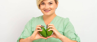 女营养学家医生穿绿色工作服持有绿色有机鳄梨水果健康的生活方式概念