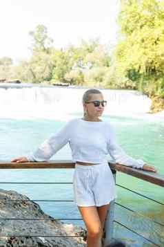 美丽的年轻的女人白色短裤衬衫背景山瀑布背景密集的森林美丽的景观