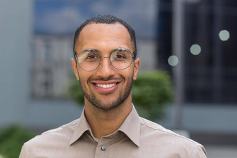 特写镜头照片肖像年轻的企业家穿眼镜拉美裔男人。微笑相机启动企业家现代办公室建筑
