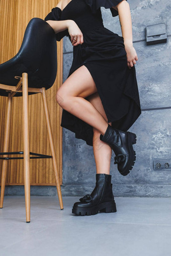 黑色的皮革<strong>靴子高跟</strong>鞋扣纤细的女腿木椅子灰色的背景概念集合鞋子春天女人黑色的衣服狭缝