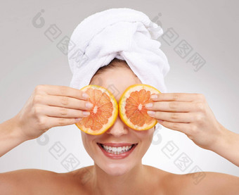 自然产品脸裁剪工作室拍摄年轻的女人持有橙色片眼睛