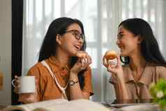 照片女朋友享受吃美味的甜甜圈坐着咖啡商店