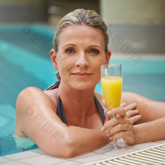享受一天奢侈品休闲肖像成熟的女人享受玻璃橙色汁在游泳池边