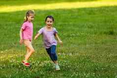 姐妹运行草坪上城市公园户外自由无忧无虑的快乐童年