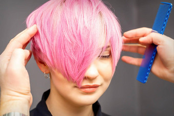 理发师手梳子检查修复短粉红色的发型年轻的白色女人头发沙龙