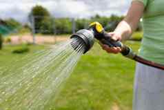 女人浇水草坪上花园软管浇水